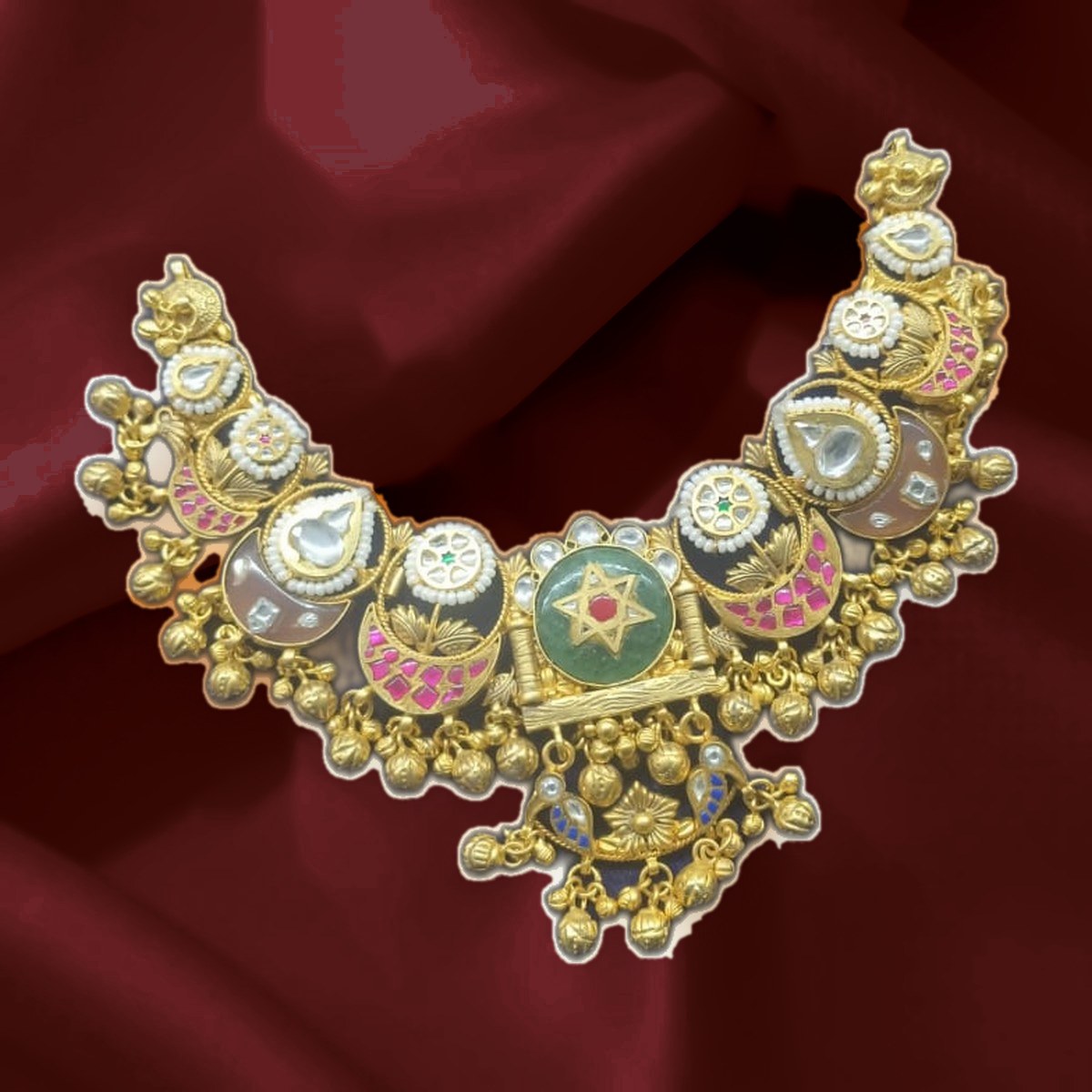 Kundan necklace set laid out on red silk in the workshop