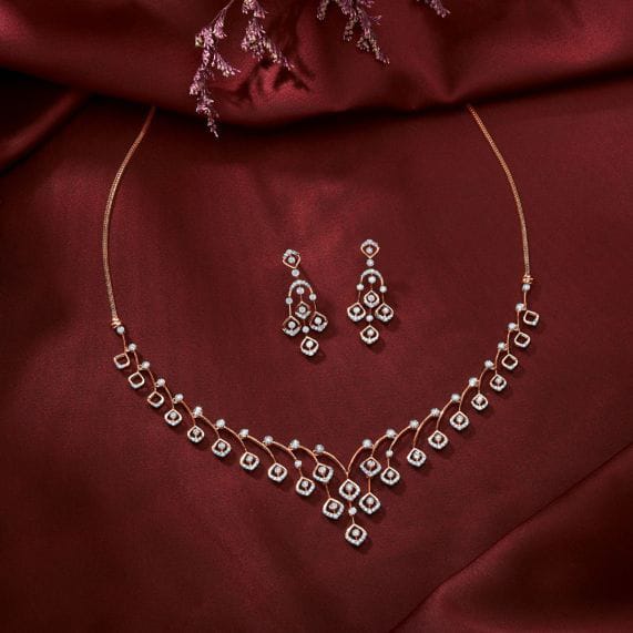 Diamond-set necklace and matching drop earrings on deep red silk